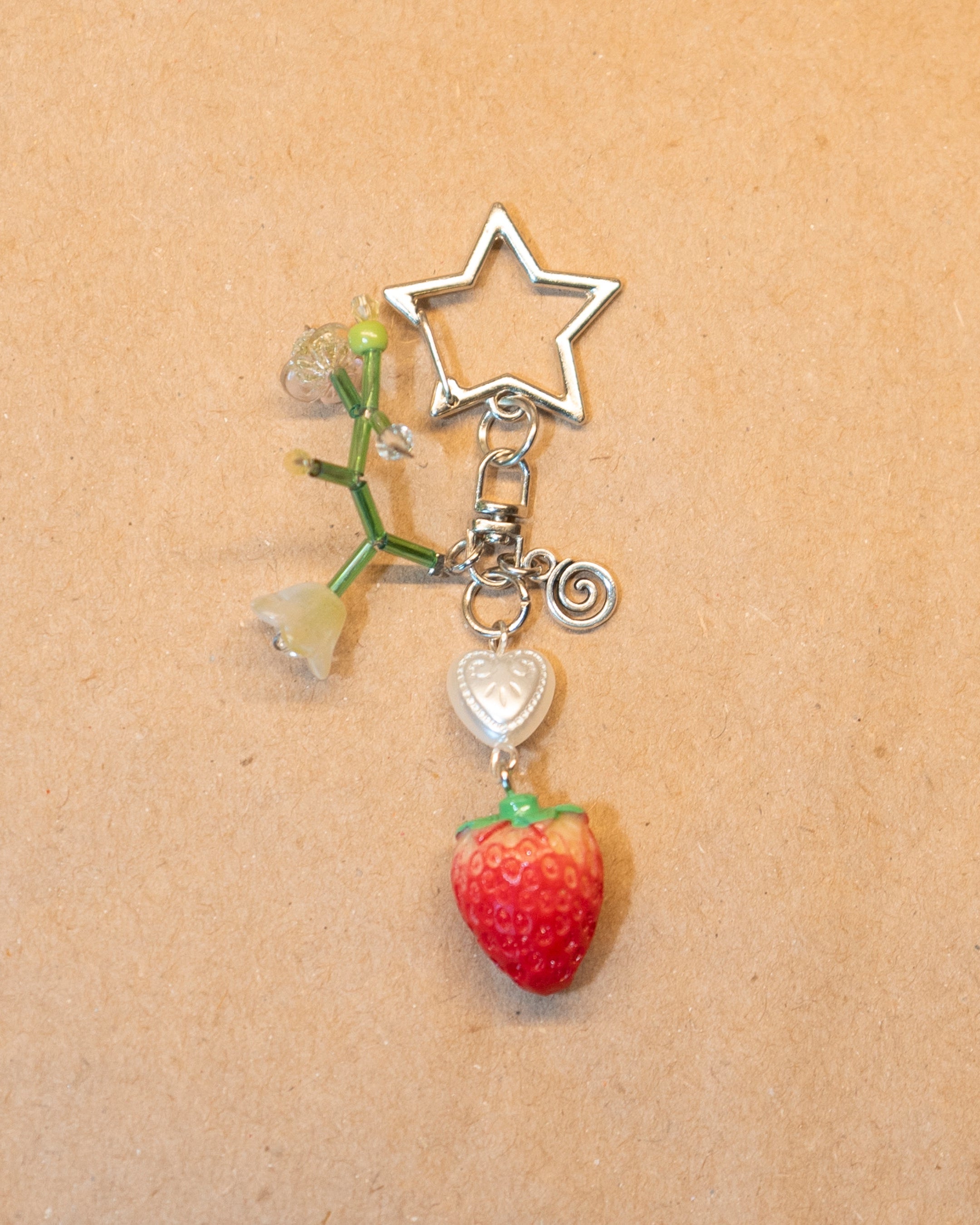 Strawberry charm with star and heart on a beige background
